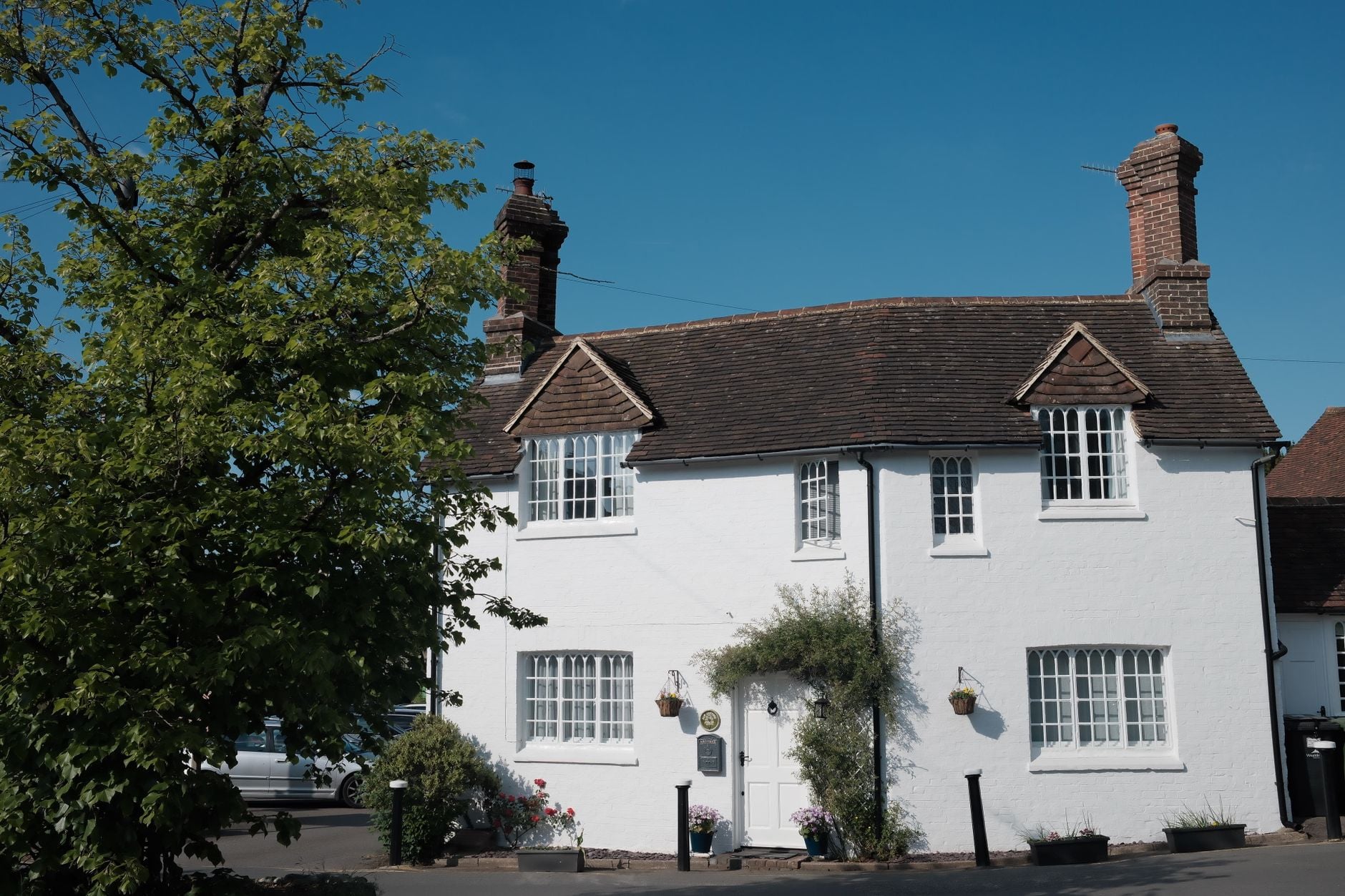 Charming white cottage with rustic brick chimneys under clear blue sky.